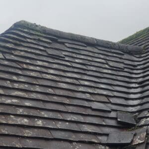 Damaged plain tile roof showing missing and broken tiles.